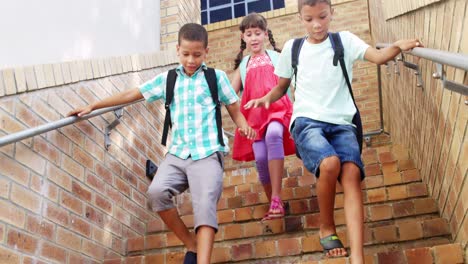 Smiling-schoolkids-walking-on-staircase-at-school