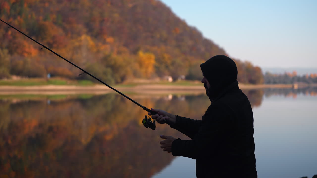 Pria memancing di tepi danau pada musim gugur.