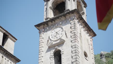 close up of the famous watch tower in old town of kotor inside of the city walls whats a beloved sightseeing spot by touristits while the national flag of montanegro is waving in the wind summer