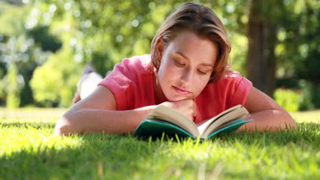 una mujer bonita leyendo un libro en el parque.