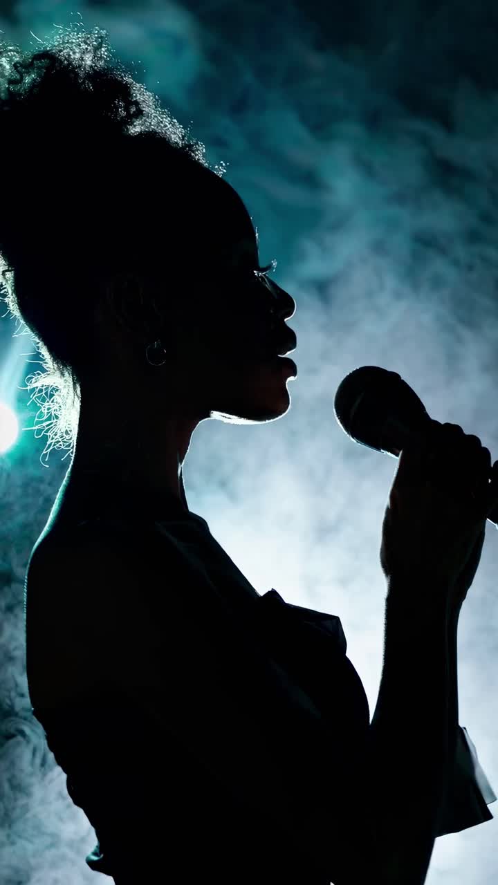 Silhouette of a singer holding a microphone against a smoky background ...