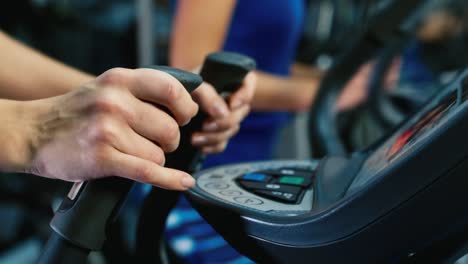 Athlete's-hands-adjusts-the-treadmill