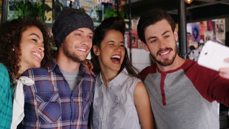 amigos tomando selfies en el teléfono móvil en el pub