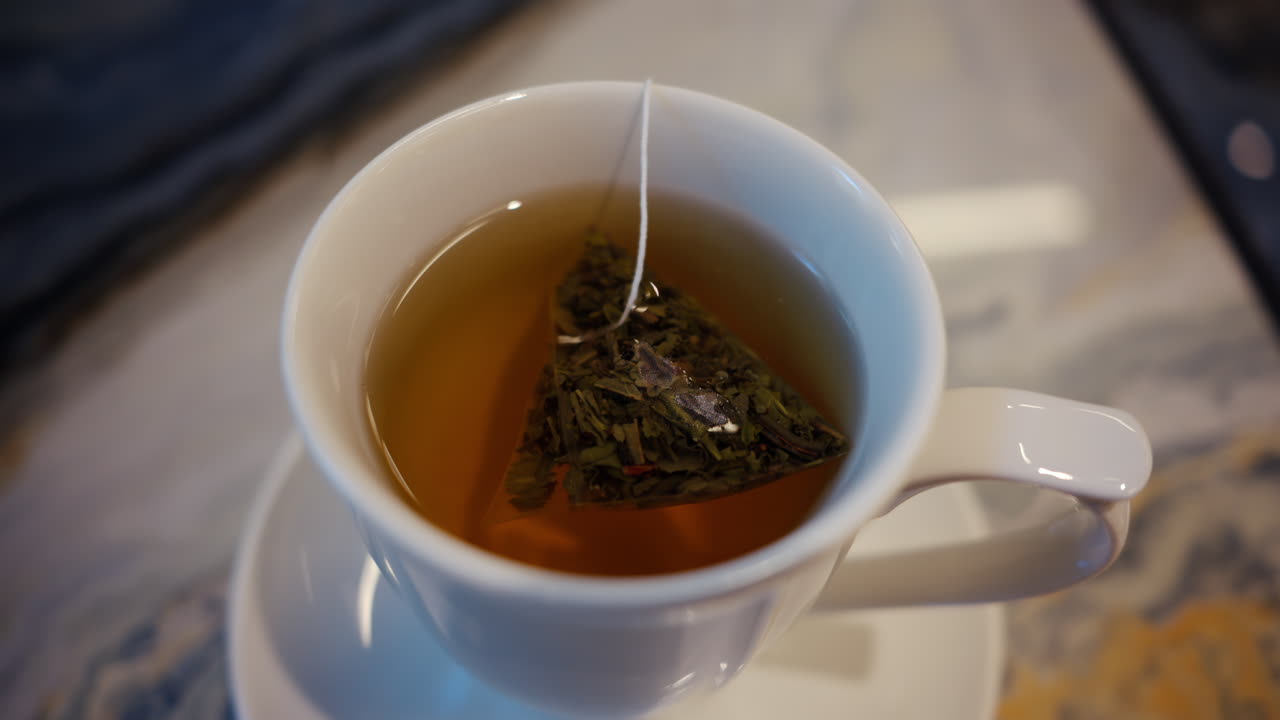 Close up of a white cup of tea standing on a marble table
