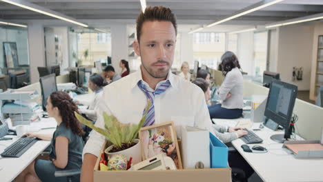 businessman getting fired carrying box of personal belongings being made redundant in recession sad worried failure