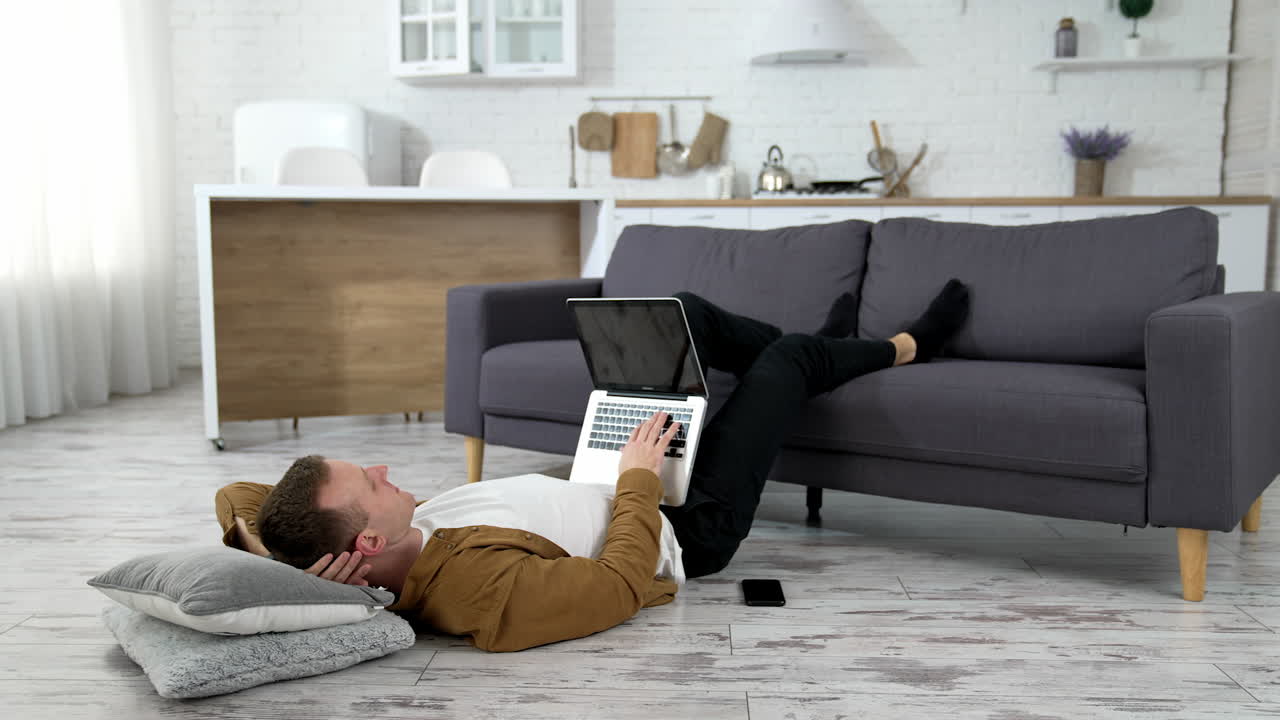 Man lying on floor with laptop. Young man working on laptop while lying onn floor