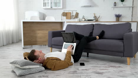 man lying on floor with laptop. young man working on laptop while lying onn floor