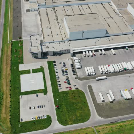 industrial complex on green field. modern plant and parking place with many trucks and cars nearby. top aerial view.