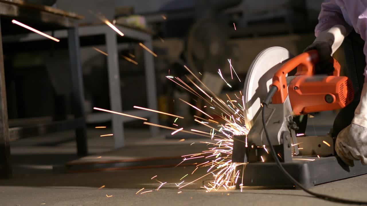 hombre trabajó duro y aserrar acero. trabajador que utiliza cortador de metal circular tiene chispa de iluminación. concepto de ingeniería, taller, industria, fabricación y negocios.