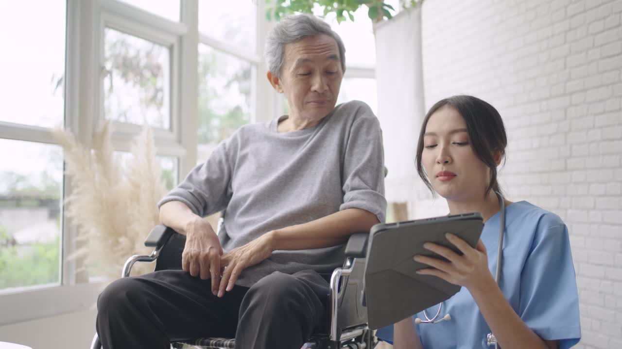 Young Asian nurse diagnose disease by talking to a senior male patient on a wheelchair.
