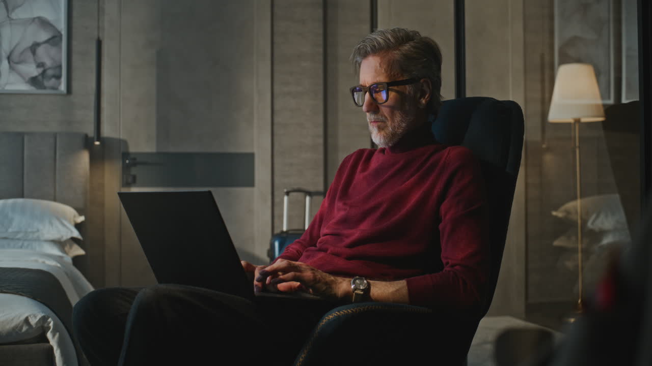 Mature Man Working on Laptop in Hotel Room