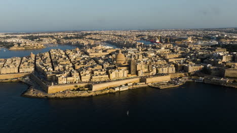 Vista-Aérea-Volando-Alrededor-Del-Paisaje-Urbano-De-La-Valeta,-Espectacular-Puesta-De-Sol-En-Malta