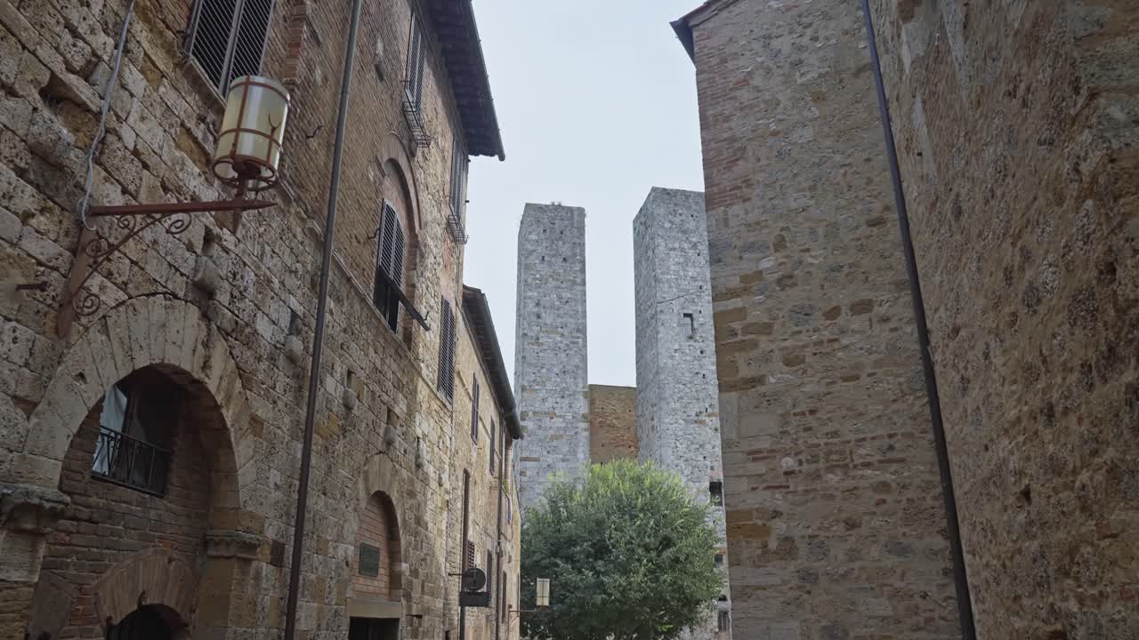 persone che camminano per le strade della città medievale con torre dei salvucci sullo sfondo a san gimignano, in italia