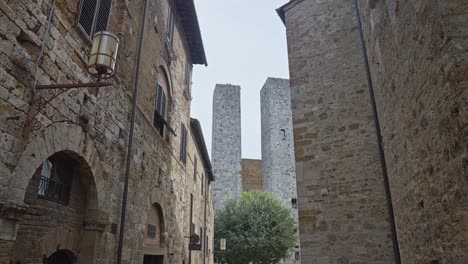 people walking on the streets of the medieval town with torri dei salvucci at background in san gimignano, italy