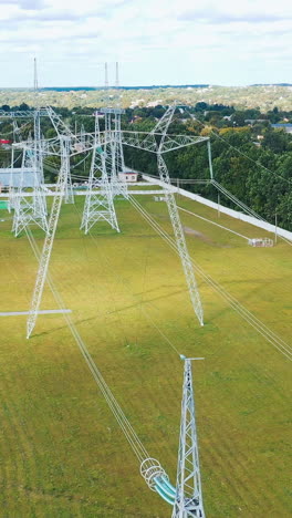electricity pylons in the countryside. power station with white tall towers on field. distribution of electricity. motion camera back. vertical video