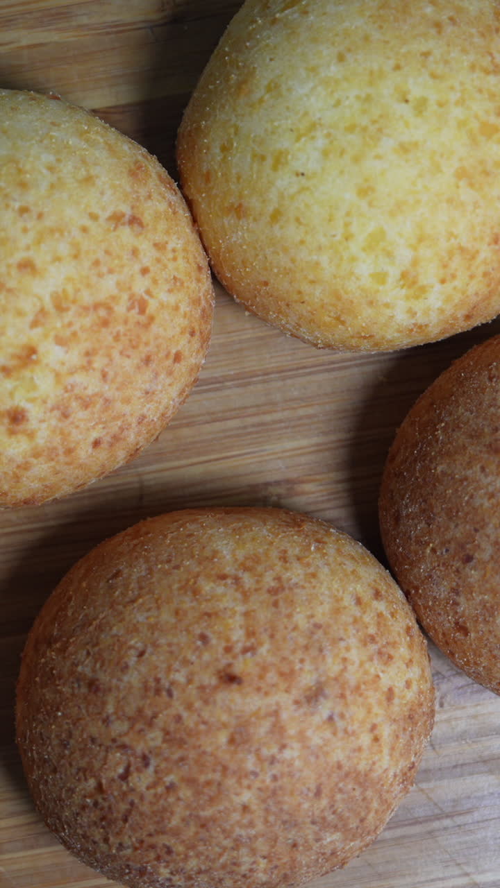 Delicious, golden-brown almohábanas on a wooden board in a vertical video format, perfect for mobile and social media. This close-up shot highlights their texture and color