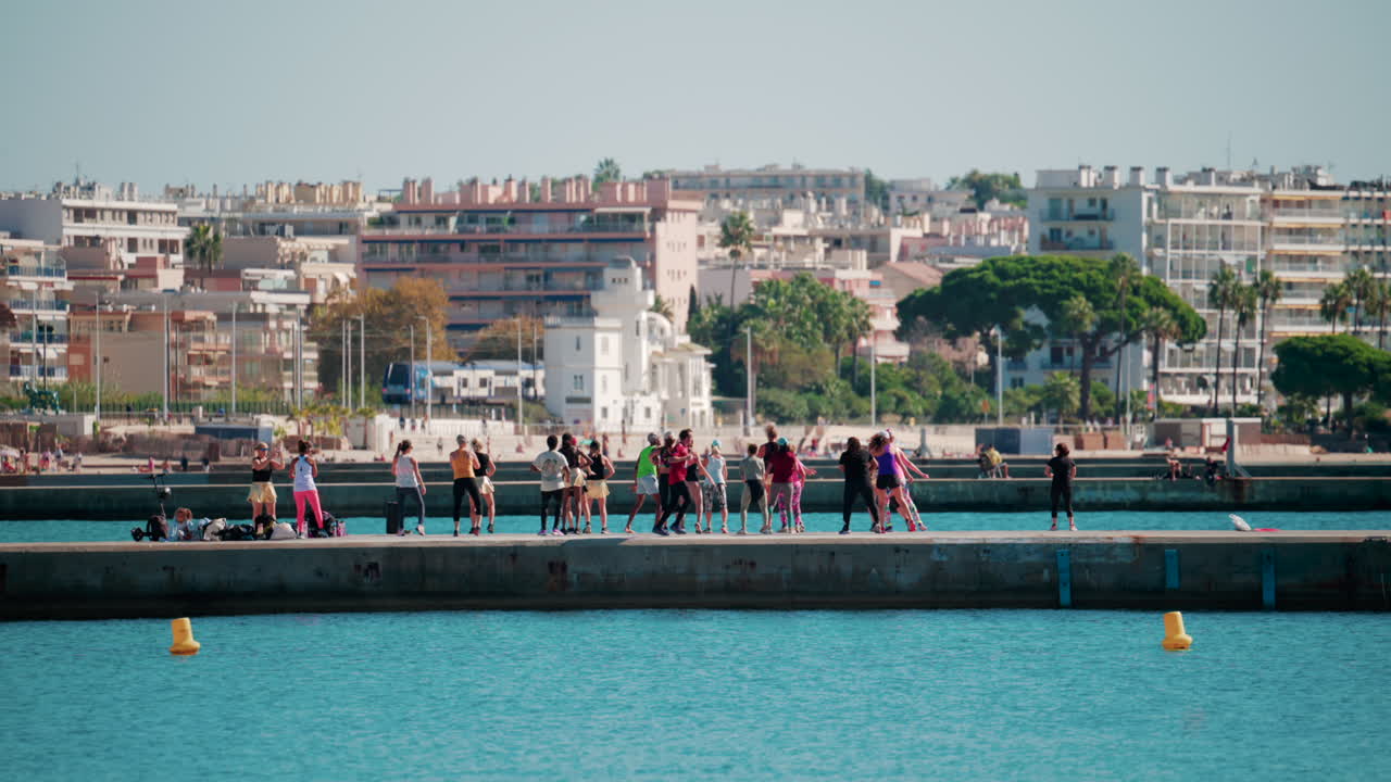 Cannes, France - October 7, 2025: A group of people practicing dance or fitness on a pier by the sea on a sunny day