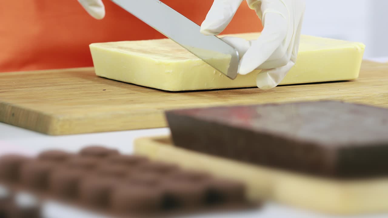 alguien cortando una barra de chocolate en pedazos pequeños.