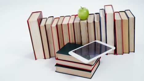 manzana, tableta digital y libros sobre fondo blanco