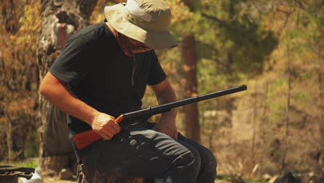 un hombre amartilla y recarga su pistola de aire comprimido mientras caza por placer en un bosque, ee.uu.