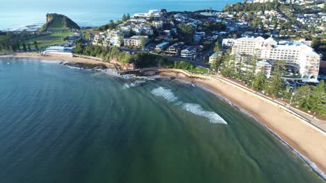 drone aerial view of ocean waves at terrigal beach bay main town streets with hotel and residential housing apartments at foreshore headland coastline central coast australia tourism vacation travel