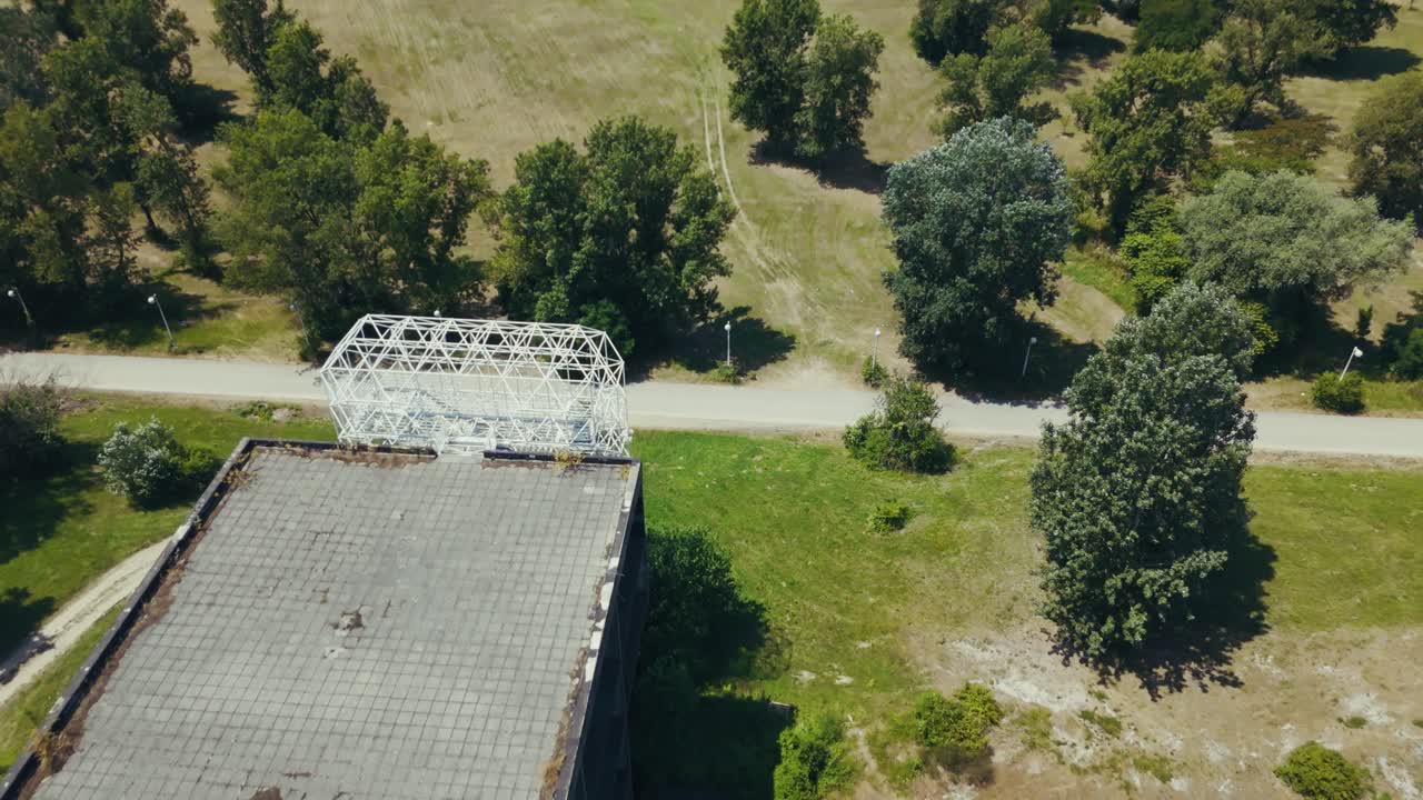 aerial - weathered rooftop of an abandoned building with open fields and scattered trees below