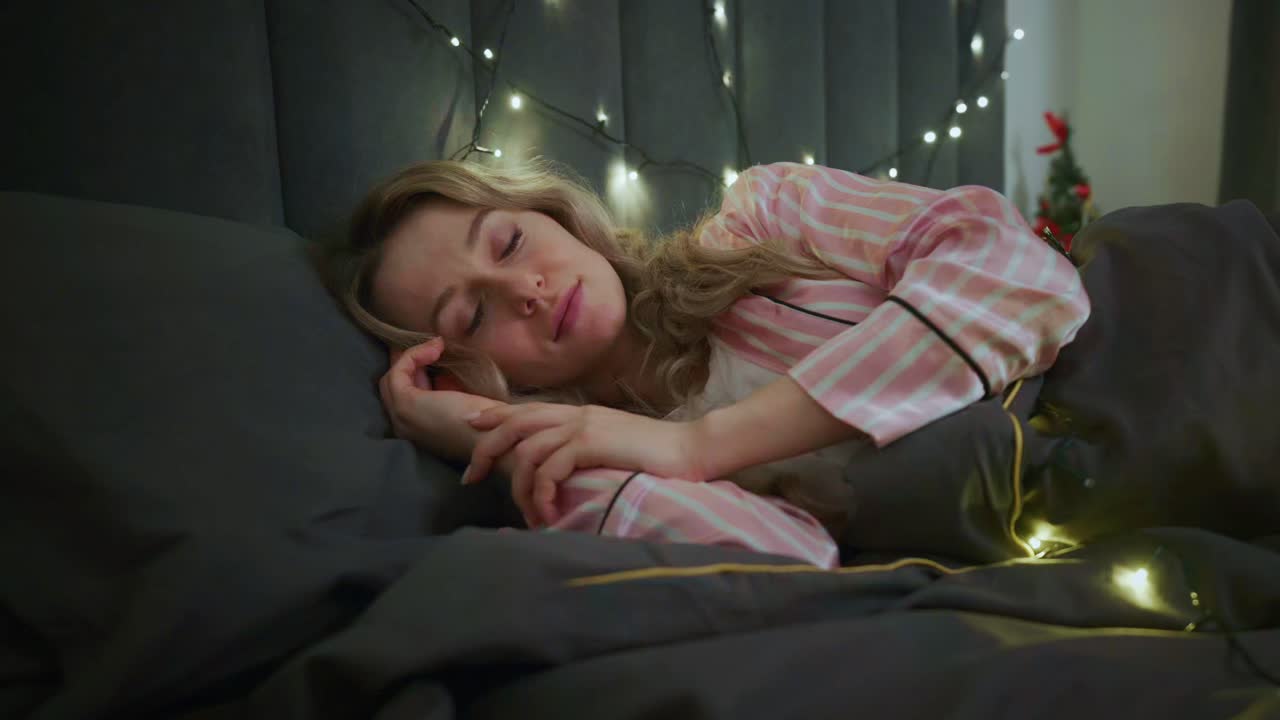 Kvinde sover i seng med julelys