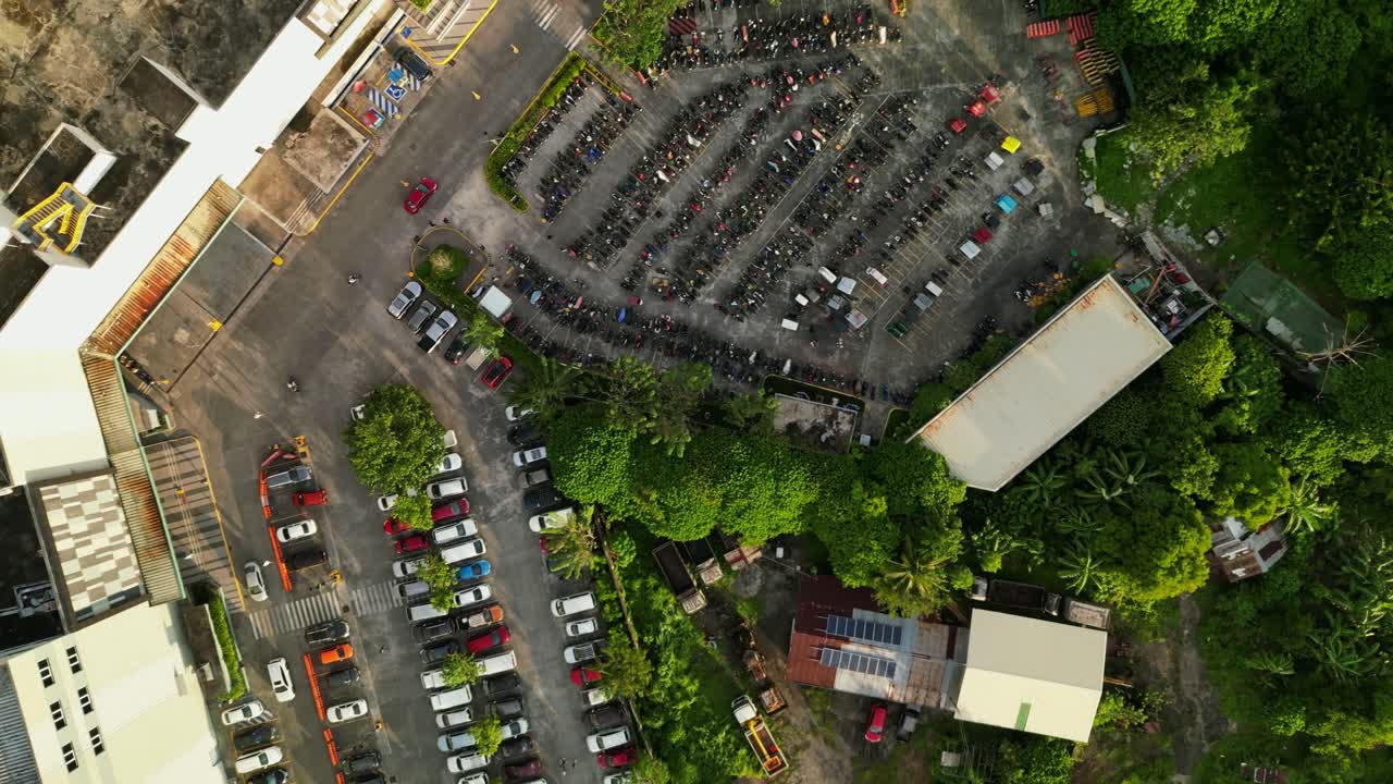 Aerial top-down shot of full parking lot with cars, trucks, and motorcycles along Robinsons Shopping Mall Outlet, Naga City, Philippines