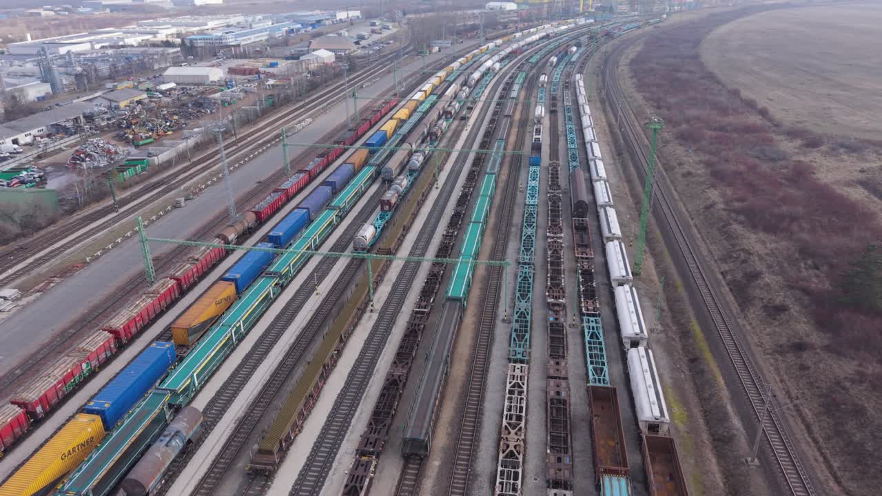 Hochwinkel-Luftaufnahme eines geschäftigen Güterbahnhofs mit langen Güterzügen, die auf mehreren parallelen Gleisen angeordnet sind