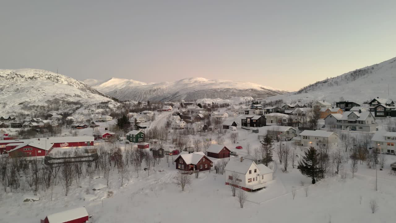 fotografía aérea de un pequeño pueblo con montañas cubiertas de nieve detrás