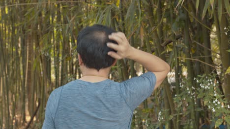 대나무 정원을 걷고 있는 대머리 남자는 가려운 두피를 긁는 것을 멈출 수 없다