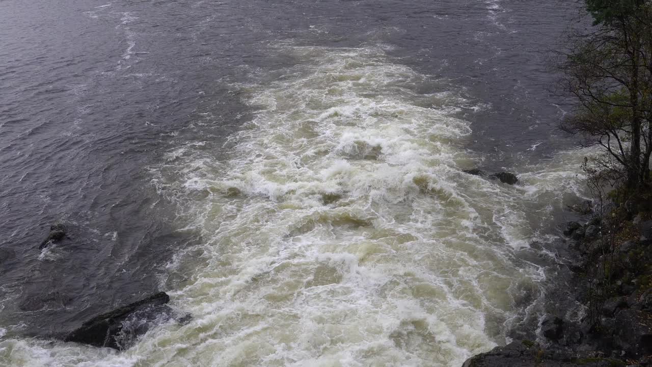 River floodwater rushing out to fjord during heavy rain, Norway