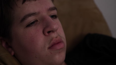 el primer plano de un joven triste, atribulado, serio y contemplativo, adolescente viendo la televisión.