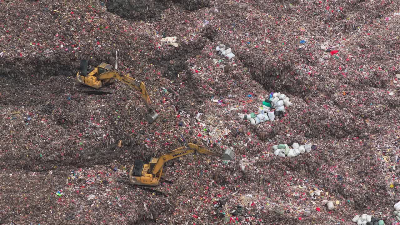 Excavators working in a massive garbage landfill