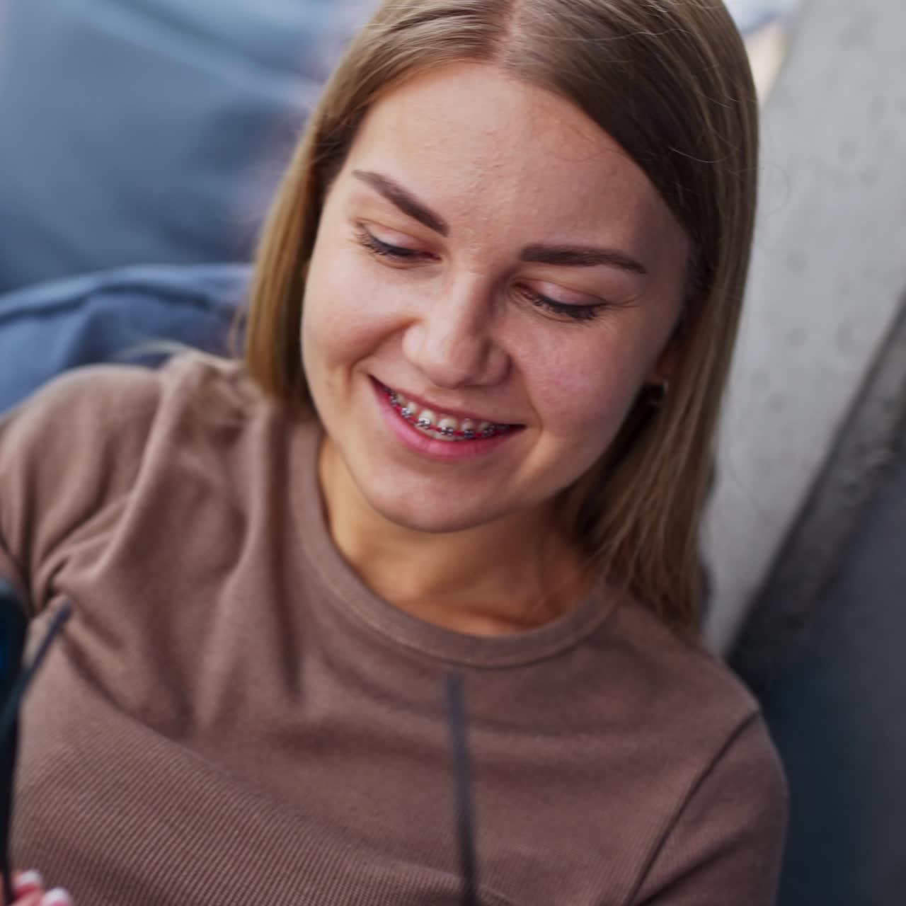 Smiling resilient girl taking selfie on her phone. Lady puts on glasses looking at camera. Close up. Blurred backdrop