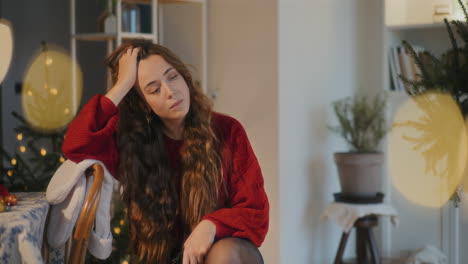 Junge-Frau-Mit-Der-Hand-Im-Haar-Sitzt-Zu-Hause