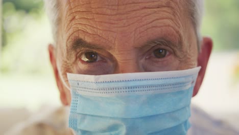 Portrait-close-up-of-senior-caucasian-man-wearing-face-mask-and-looking-at-camera-in-slow-motion