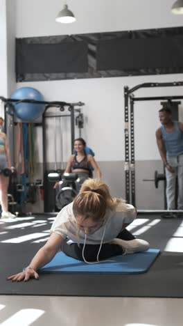 mujer estirándose en un gimnasio