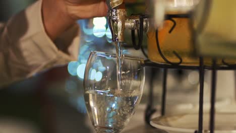 a waiter pours water into a wine glass during wedding banquet service