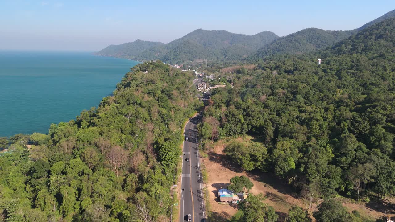 Flyover drone shot of Koh Chang's White Sand Beach, Thailand. Sunny morning over the village, sea, and lush greenery