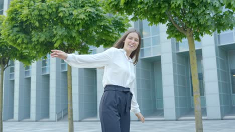 Playful-woman-balances-and-smiles-in-front-of-corporate-building