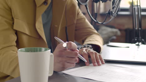 Man-Hands-Taking-Notes-On-A-Table-With-Laptop-And-Microphone