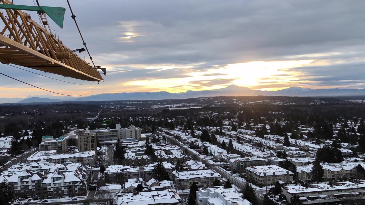 Näkymä nosturin ohjaamosta auringonnousuun pilvien lipuessa ohi