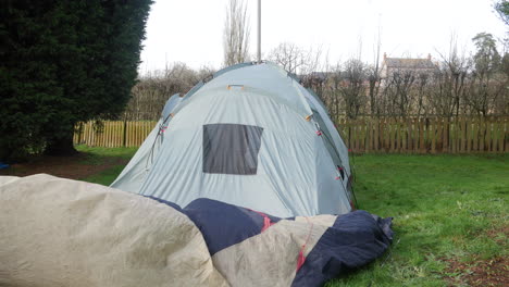 a mature man taking down a tent at a campsite removing the fly sheet on the grass