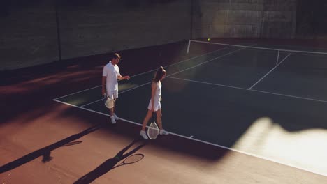 woman and man playing tennis on a sunny day