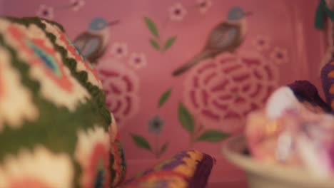 close up shot of a colorful pillow with the local embroidery and the purple wall in the background