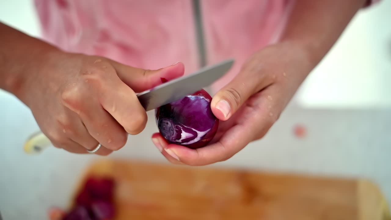 A person skillfully chops red cabbage in a well-lit home kitchen. The process showcases techniques for preparing vegetables, ideal for salads or side dishes