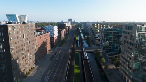 aerial - train drive on straight railroad through residential area, copenhagen