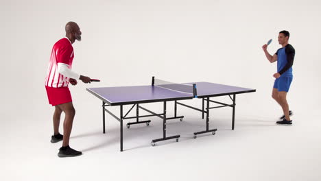playing table tennis, two men competing intensely in studio setting