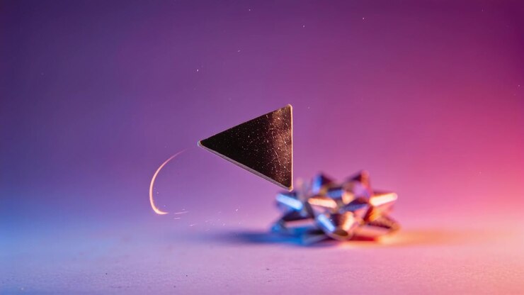 Turning triangle hovering above studio table as spark trail brightening near gift bow, copy space